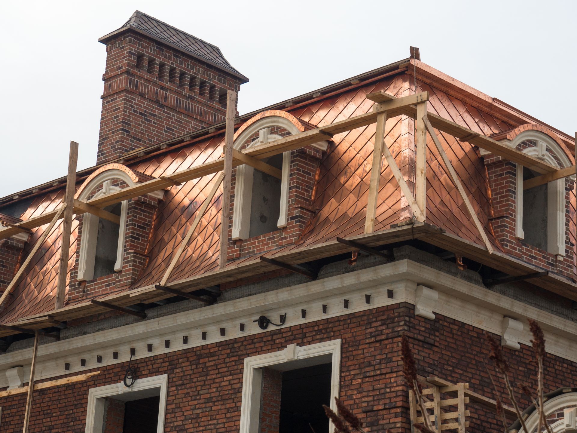 Brick house with ornate dormer windows and a chimney under a tiled roof