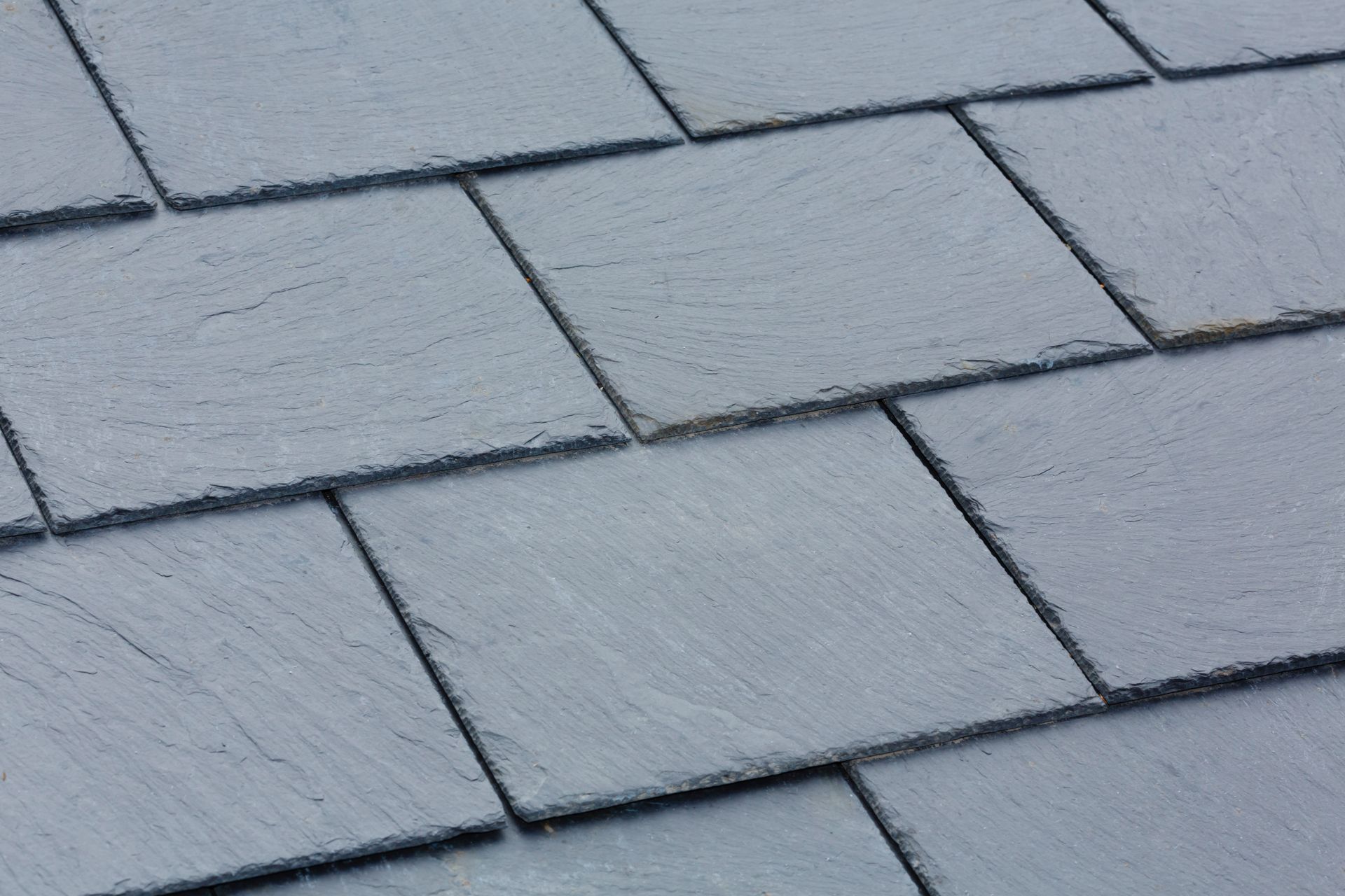 Close-up of gray roof shingles with staggered rectangular pattern and visible texture