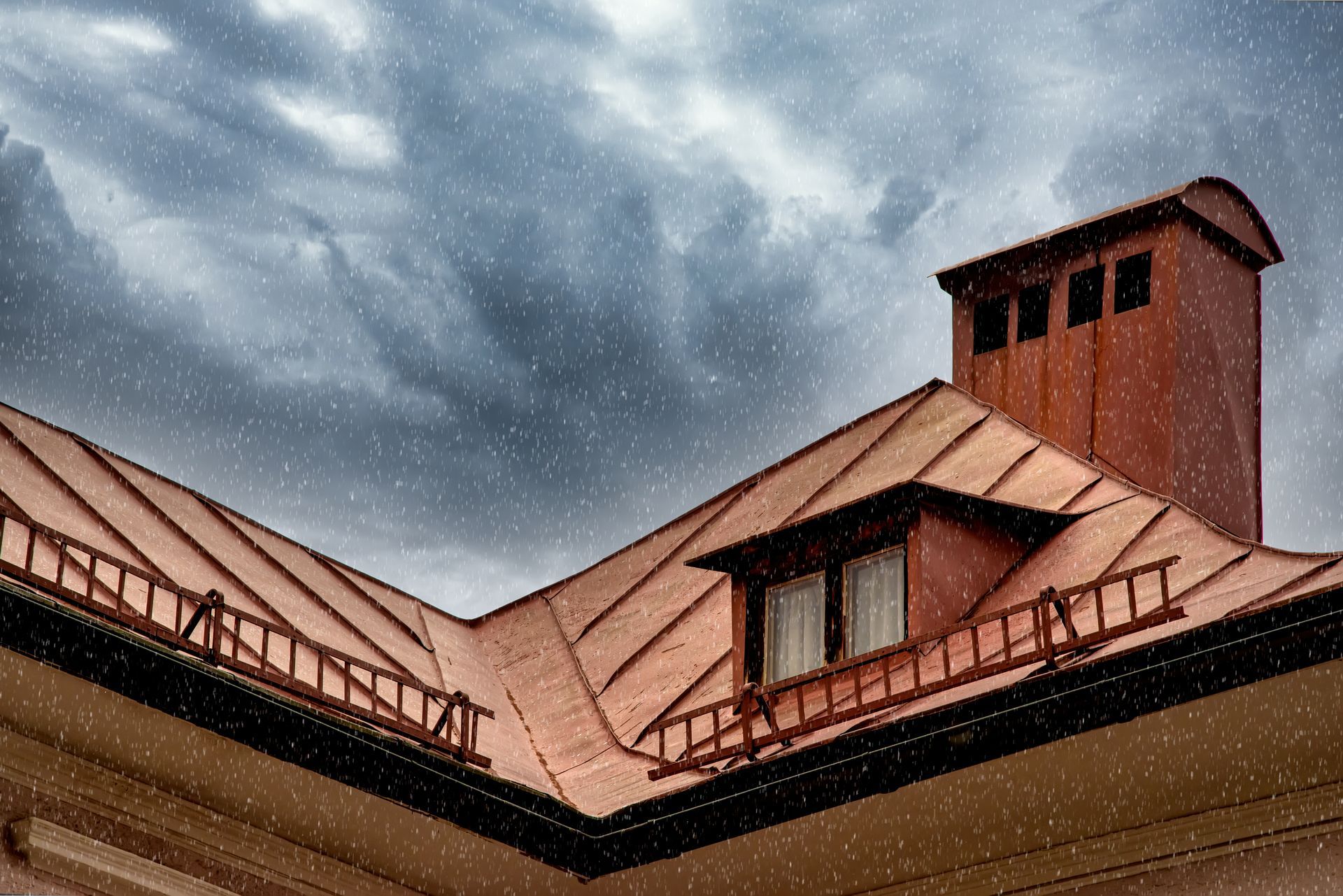 Snow falling over a copper-roofed house with a chimney against a cloudy sky