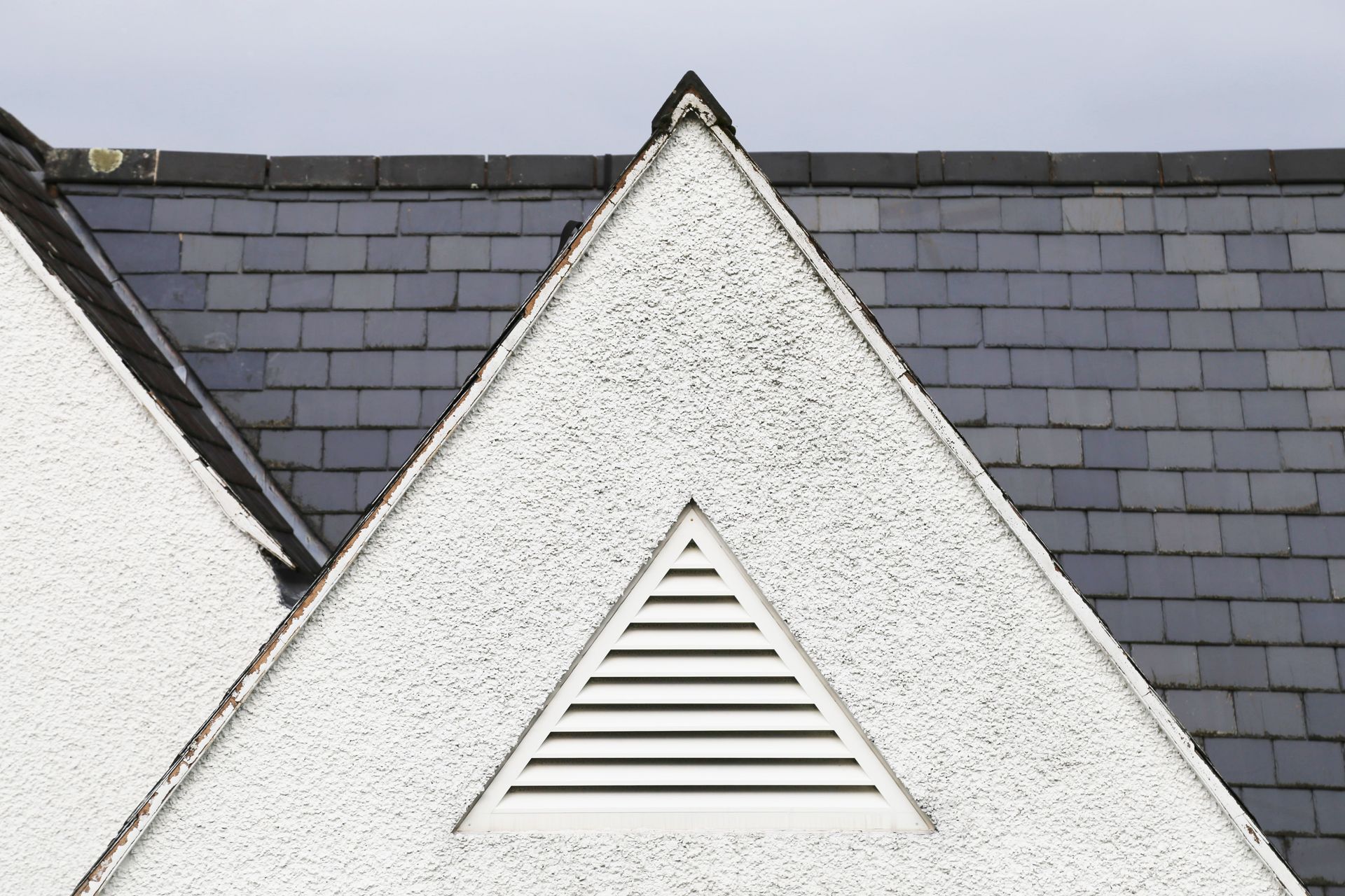 White house gables with dark gray roof shingles and a triangular attic vent