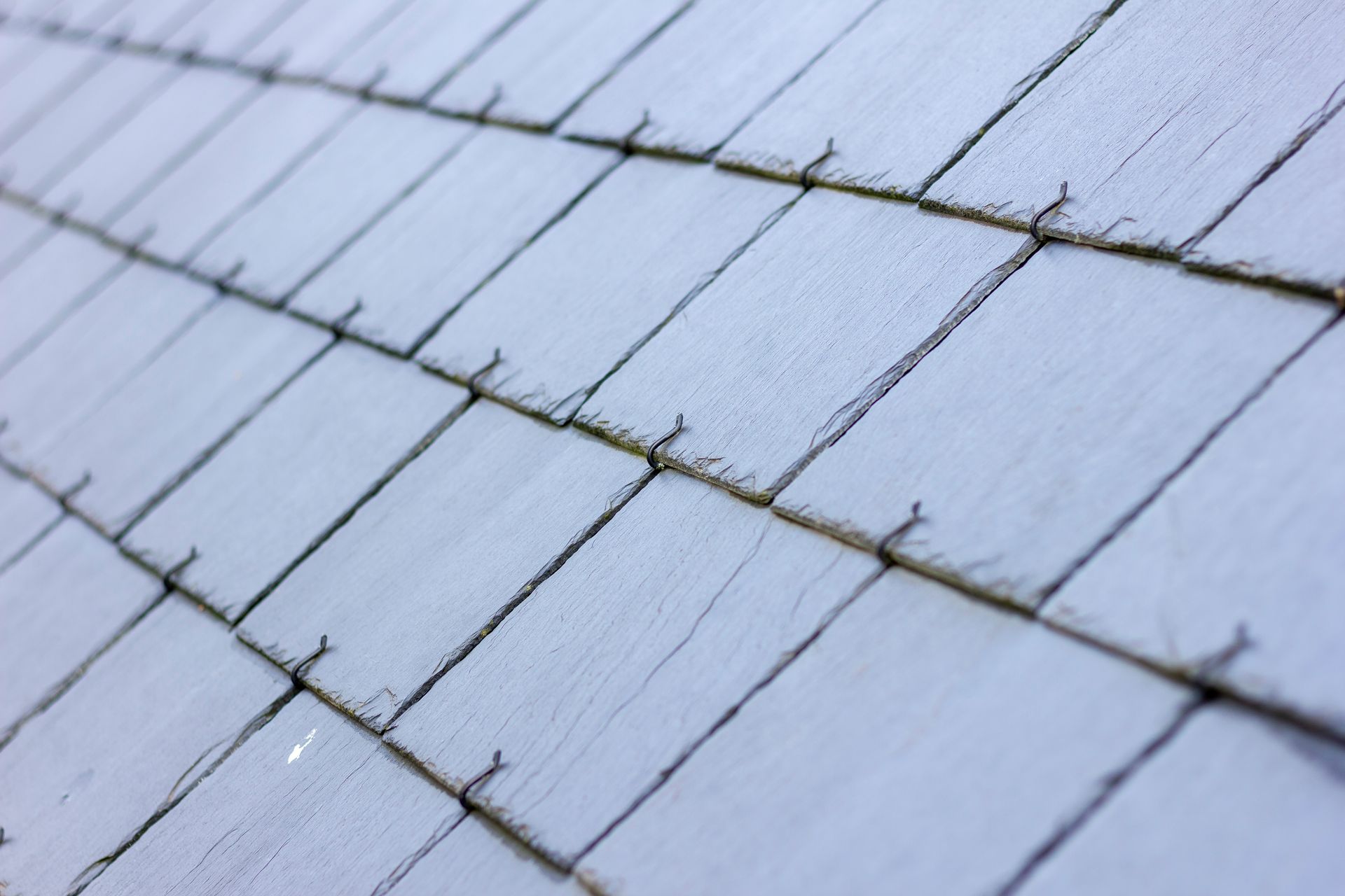 Close-up of blue-gray roof shingles with diagonal overlapping lines