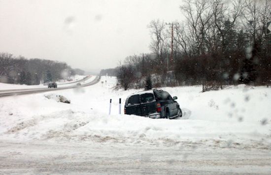 Car wreck in snowy ditch beside a rural road on an overcast winter day