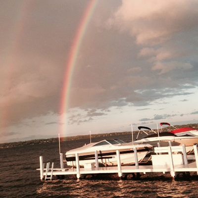 Rainbow over a docked boat on a windy lake at sunset