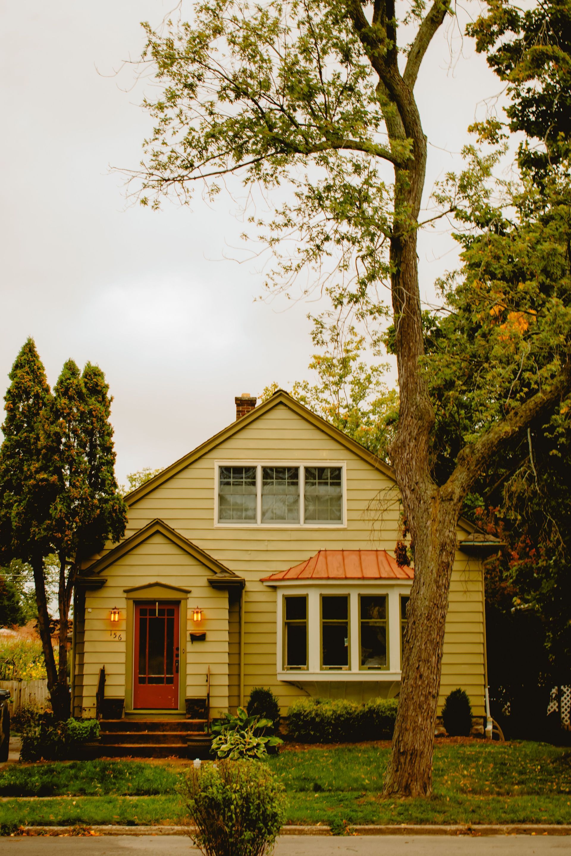 Modern stucco townhouse with tan garage doors, red tile roof, and a sunny driveway