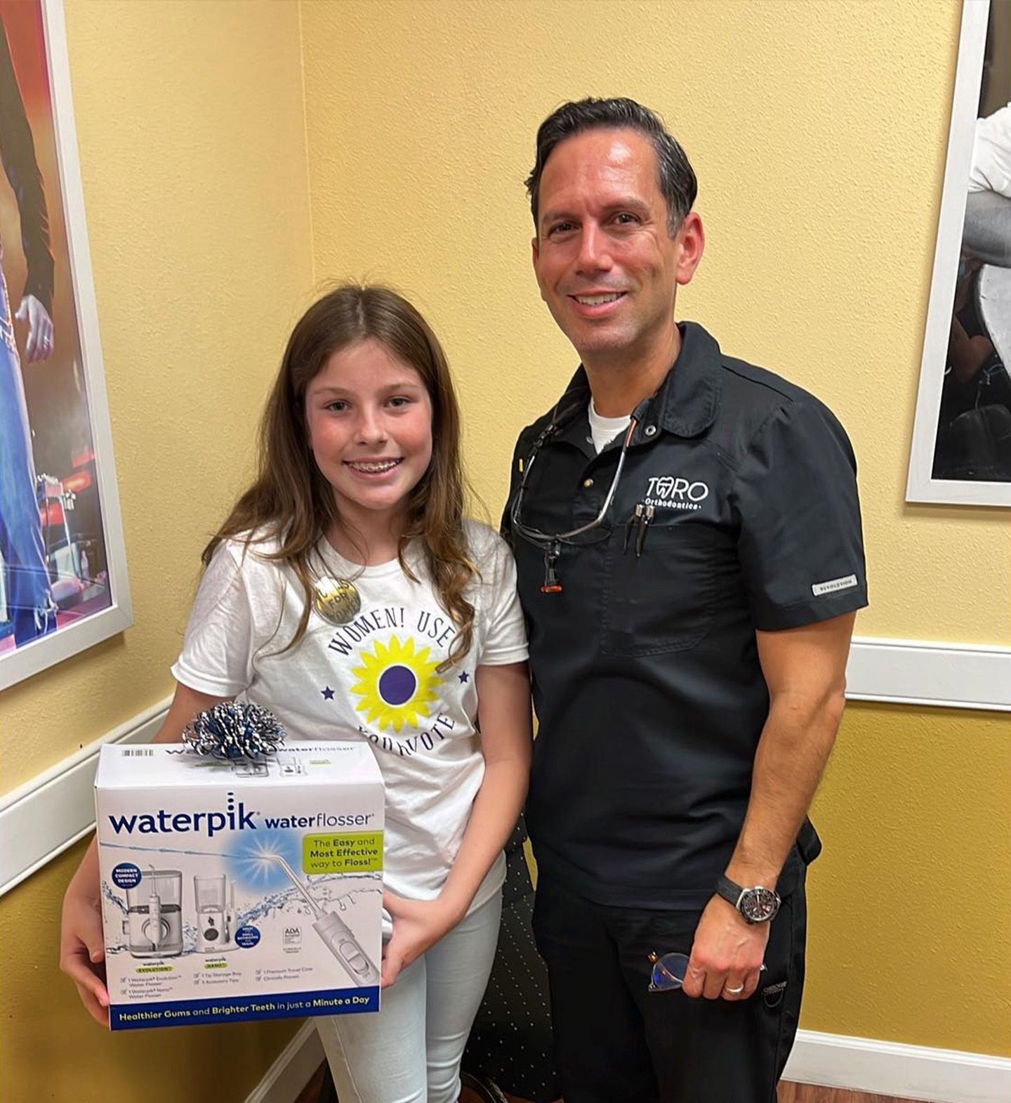 A man and a girl are standing next to each other holding a waterpik box.