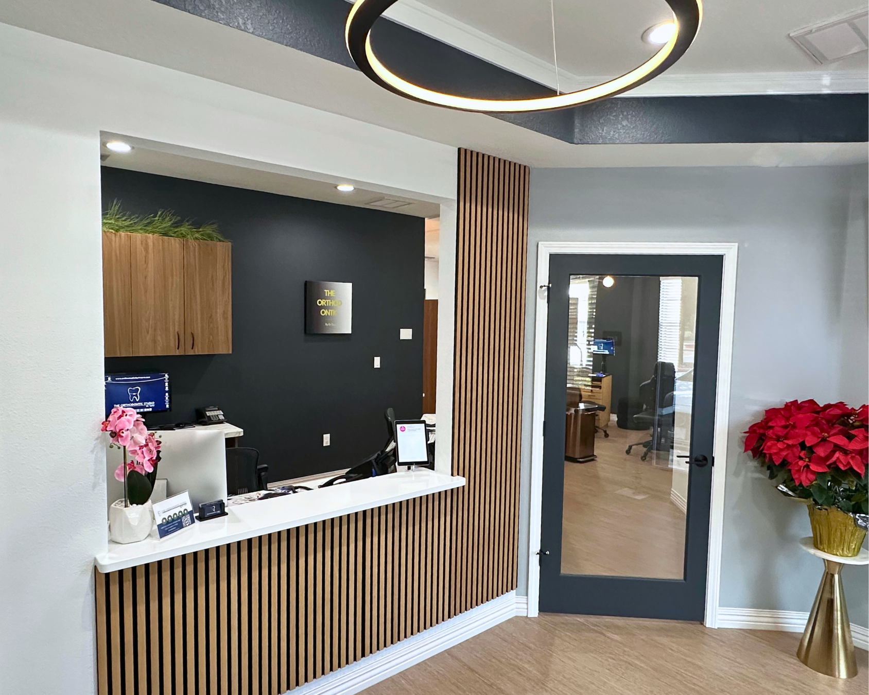 Reception area with a wooden panel reception desk and a black door with a glass panel.
