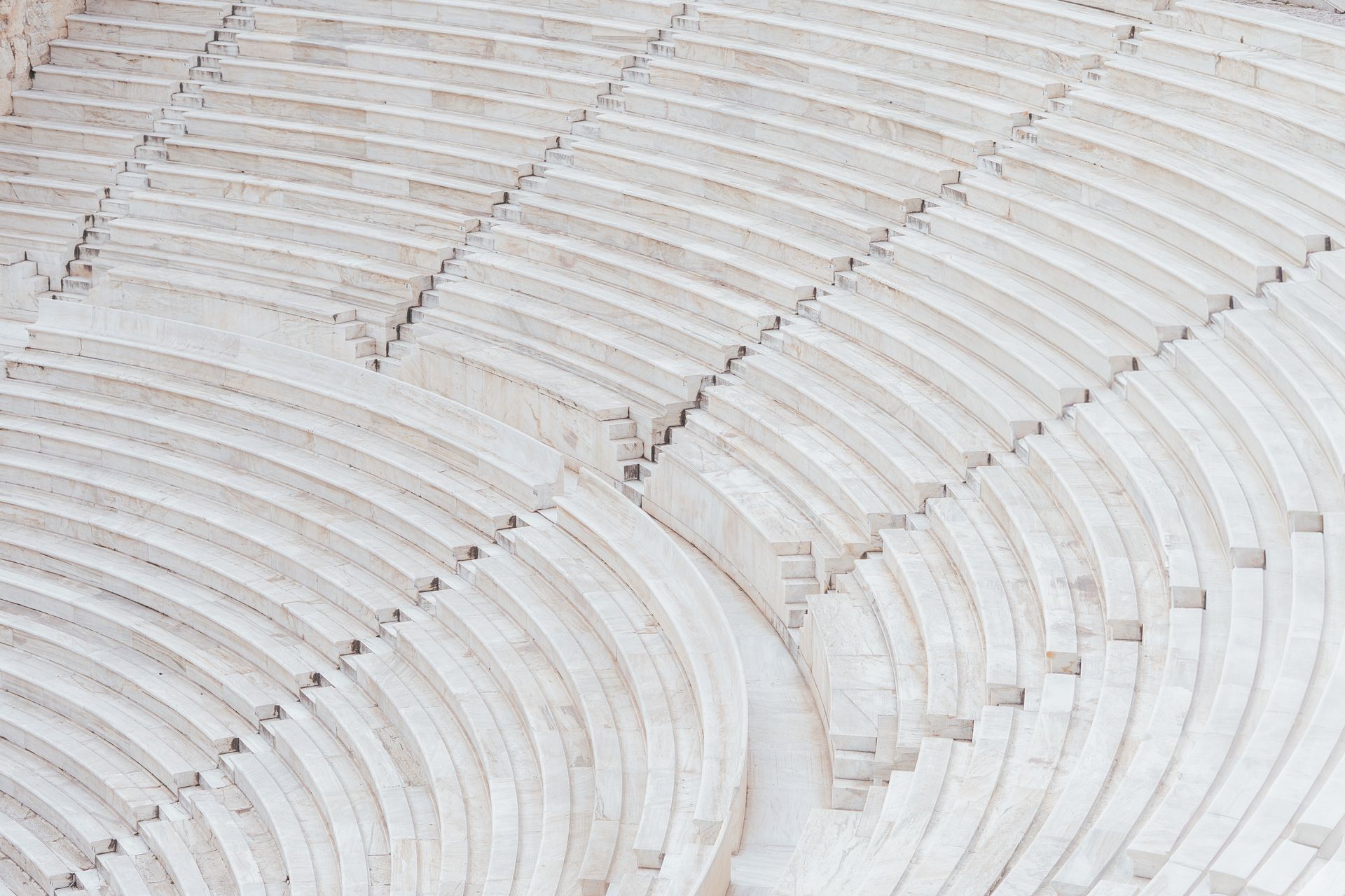 High-angle view of the curved, stone seating rows of an ancient Greek or Roman amphitheater.