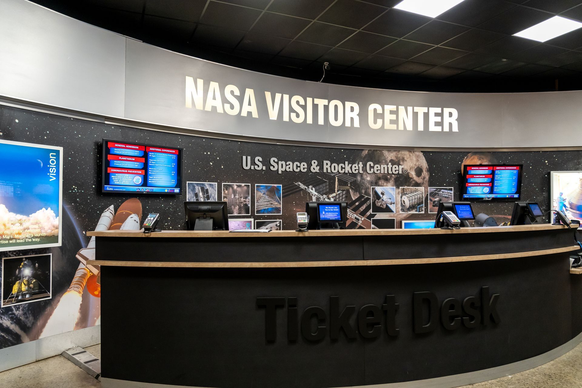 The NASA Visitor Center ticket desk at the U.S. Space & Rocket Center, featuring a curved counter and wall graphics.