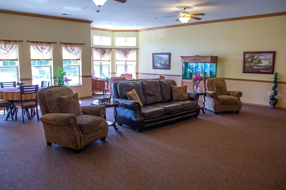 A living room with a couch , chairs , tables and an aquarium.