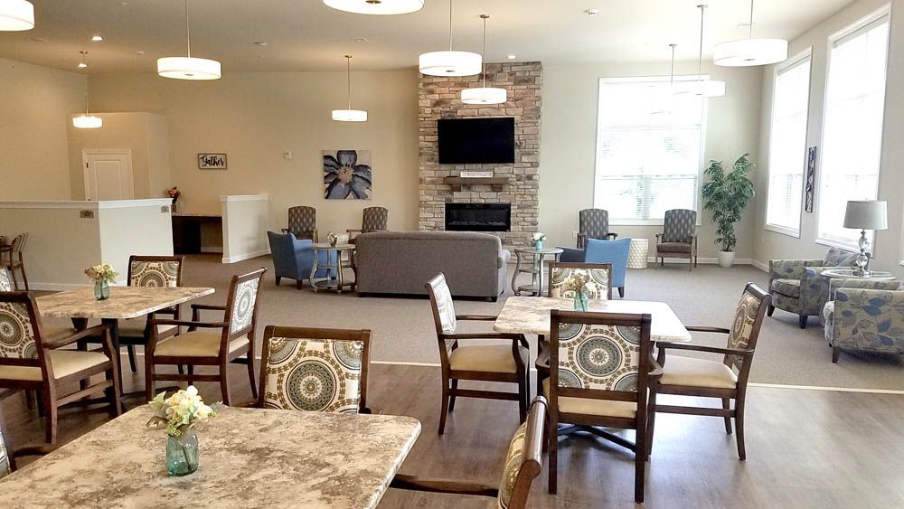 A large room with tables and chairs and a fireplace.