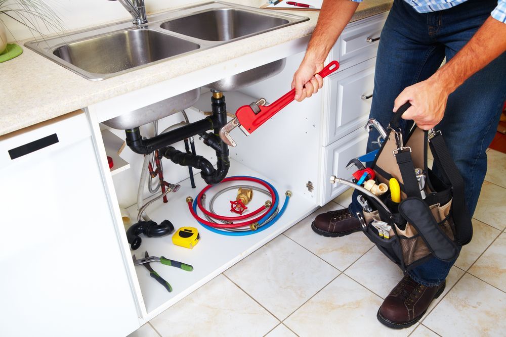 kitchen sink pipes being fixed - Plumber in Corlette