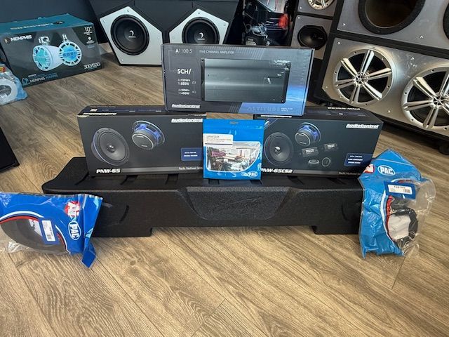 Audio equipment on a wooden floor, including speakers, amplifier, wiring, and a black speaker box. Audio equipment on a wooden floor, including speakers, amplifier, wiring, and a black speaker box.