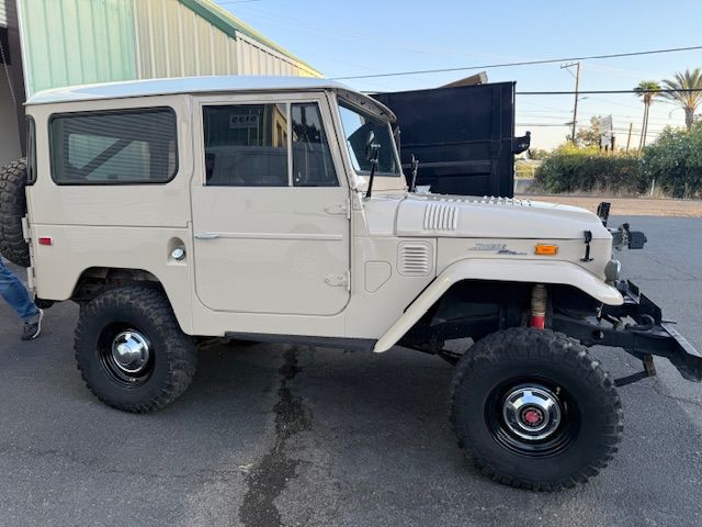 Tan Toyota Land Cruiser SUV with black wheels and a spare tire, parked outside. Tan Toyota Land Cruiser SUV with black wheels and a spare tire, parked outside.