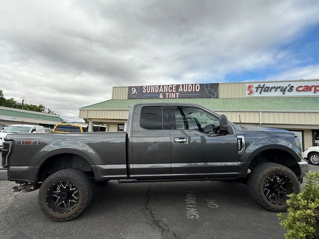 Gray Ford pickup truck with black wheels parked in front of Sundance Audio & Tint and Harry's Carpet stores. Gray Ford pickup truck with black wheels parked in front of Sundance Audio & Tint and Harry's Carpet stores.