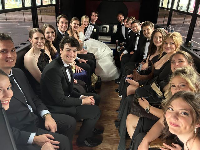 Group dressed formally seated at a long banquet table, smiling and raising glasses in a bright reception room.