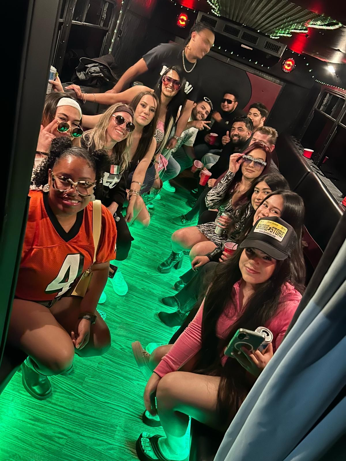 Party bus interior with green LED lighting and seated customers.