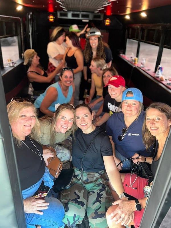 Group of people smiling and posing inside a bus with red lighting