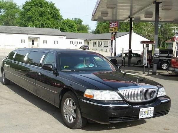 Black limousine parked at a gas station under the canopy