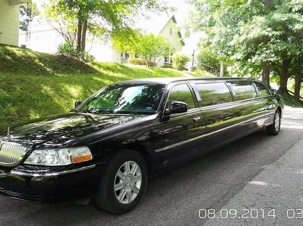 Black stretch limousine parked on a tree-lined street in daylight