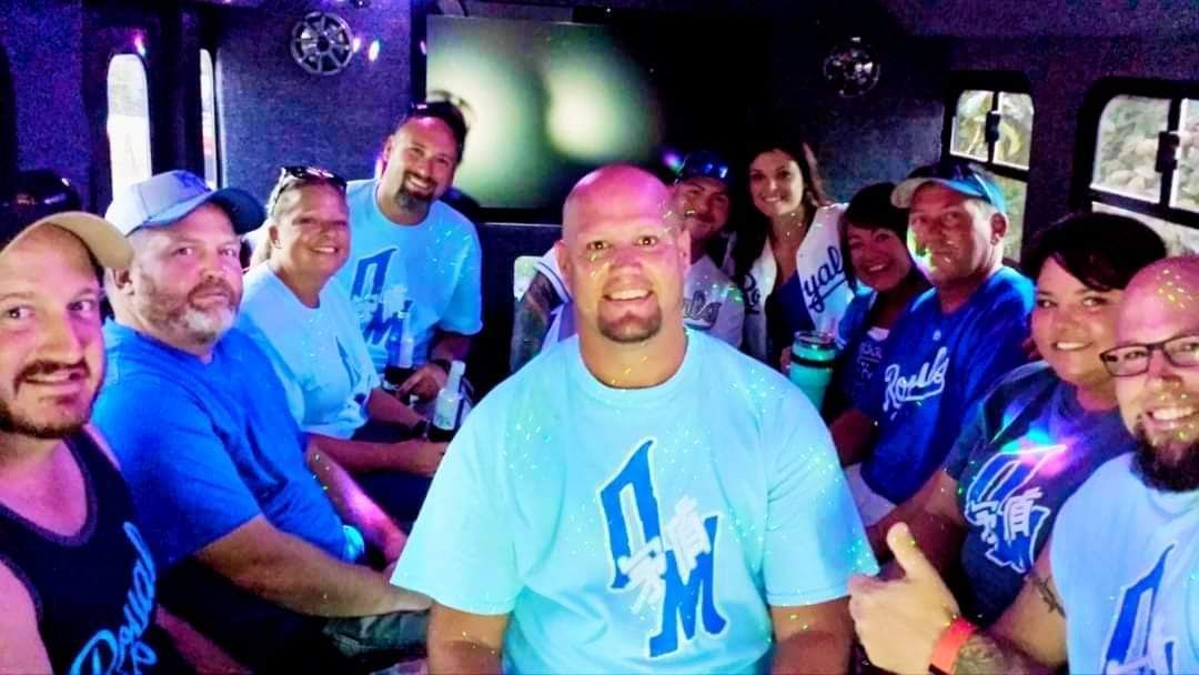 Group of people in blue shirts posing together in a dimly lit indoor venue