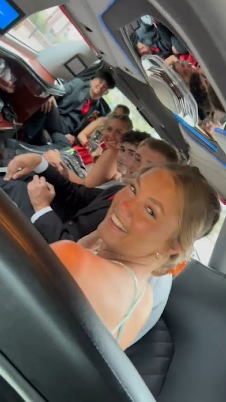 Passengers smiling inside a car, with one woman in the foreground looking at the camera.