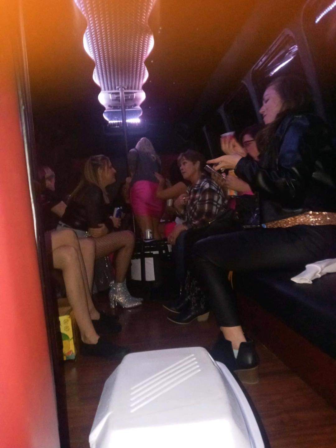 People sitting in a dimly lit lounge with red seats and a chandelier overhead