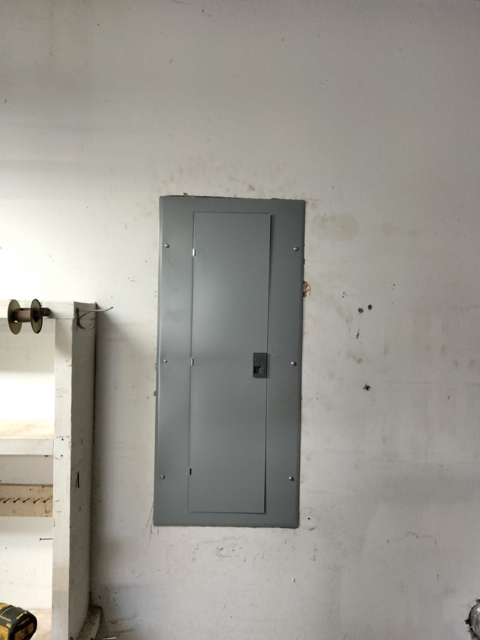 A gray electrical box is hanging on a white wall.
