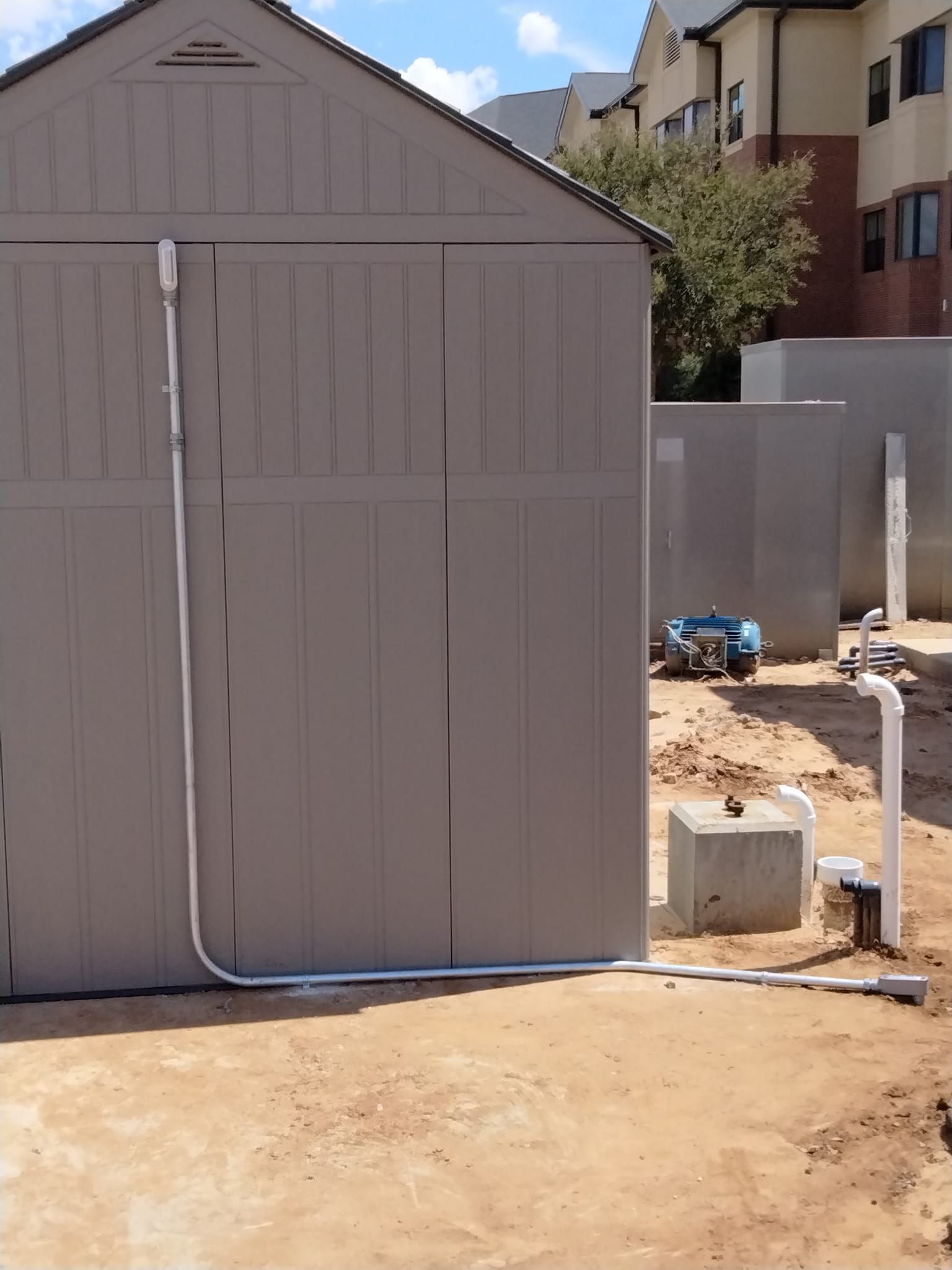 A gray shed with a white pipe attached to it
