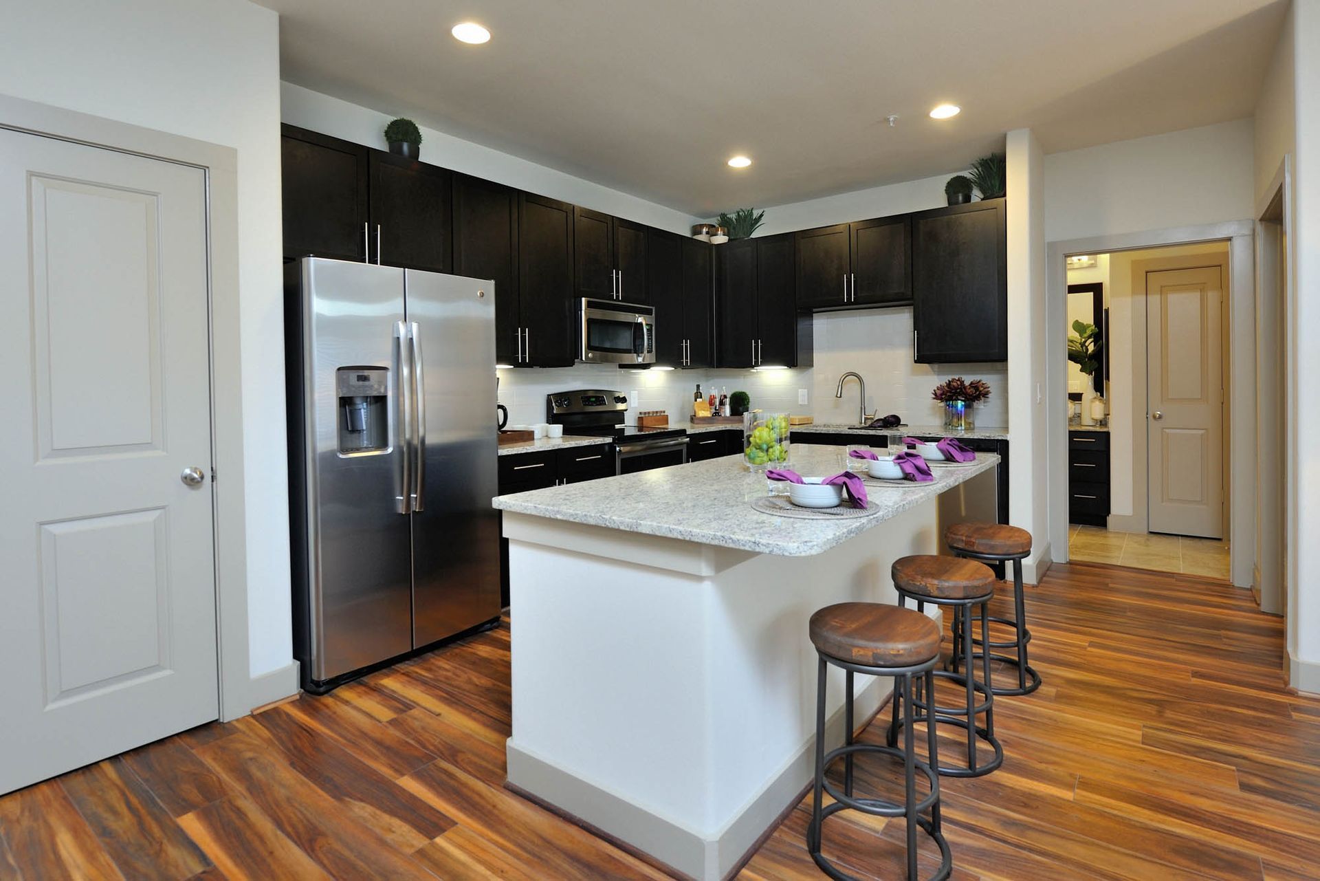 Open-concept kitchen with granite island, stainless-steel appliances, and dark wood cabinets at Olympus Falcon Landing at Olympus Falcon Landing at Olympus Falcon Landing.