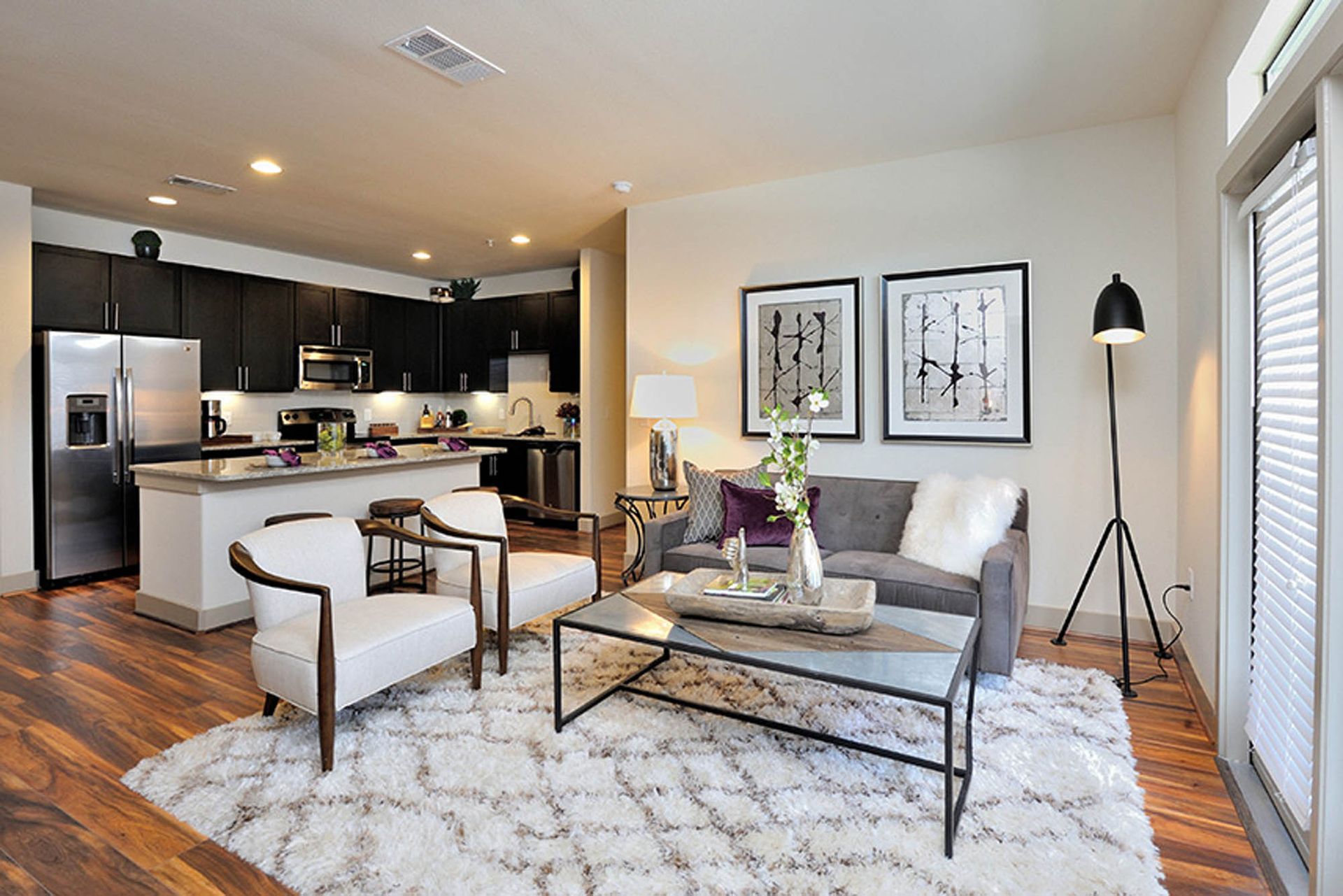 Open-concept living room and kitchen in a modern apartment with hardwood floors at Olympus Falcon Landing.
