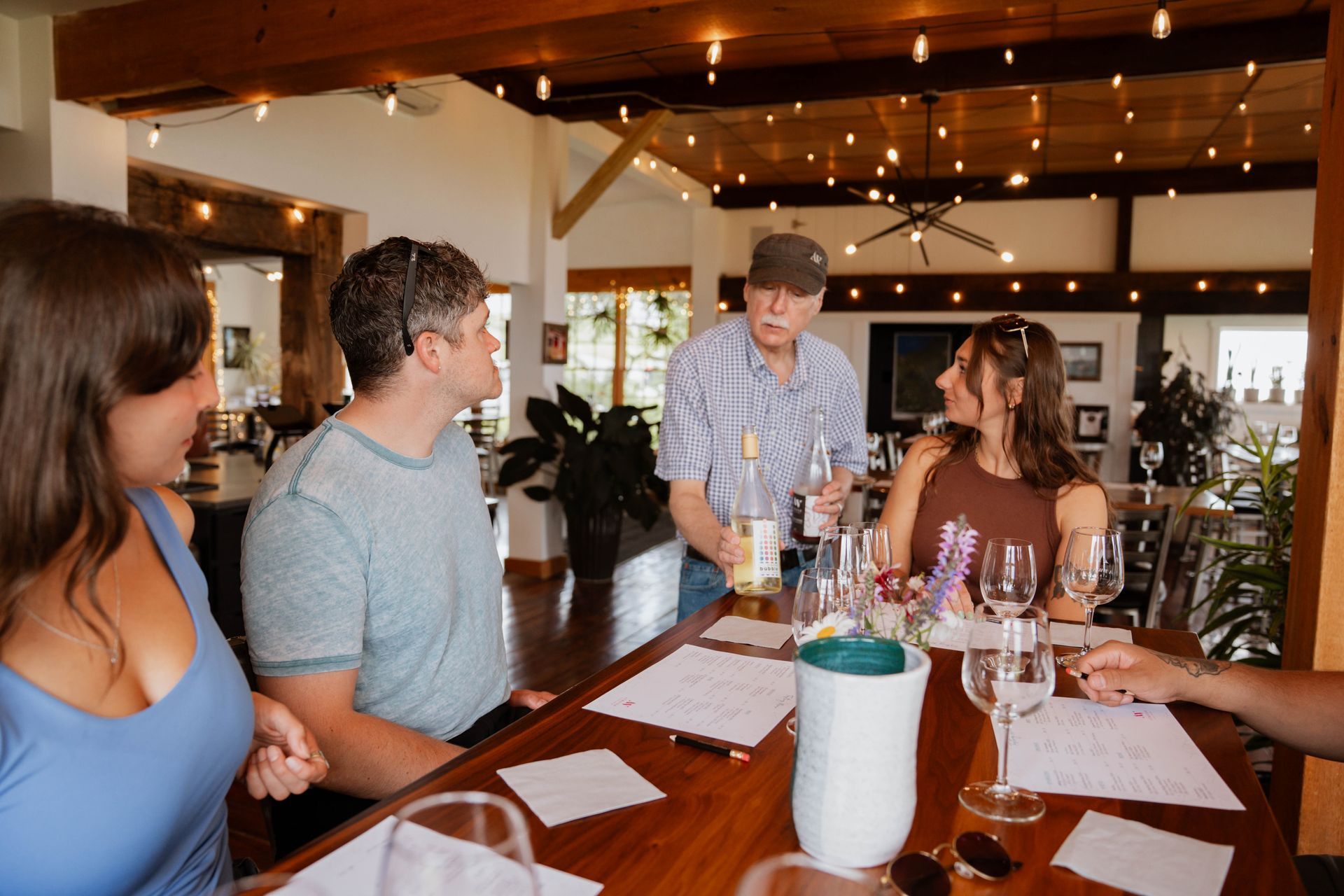 People gathered around a restaurant table with menus and drinks, talking in a cozy indoor setting