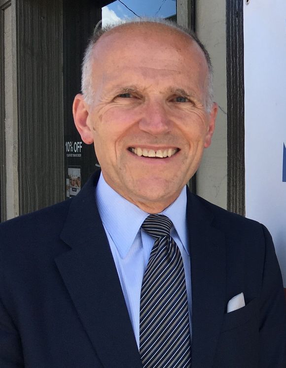 A man in a suit and tie is smiling for the camera
