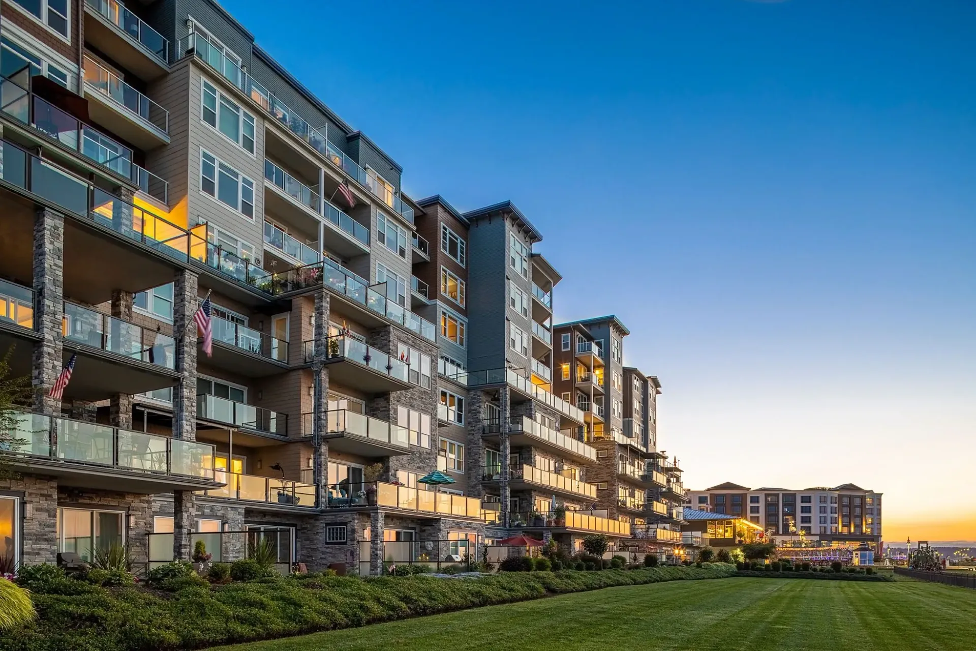 Modern apartment building exterior with balconies and a manicured lawn.