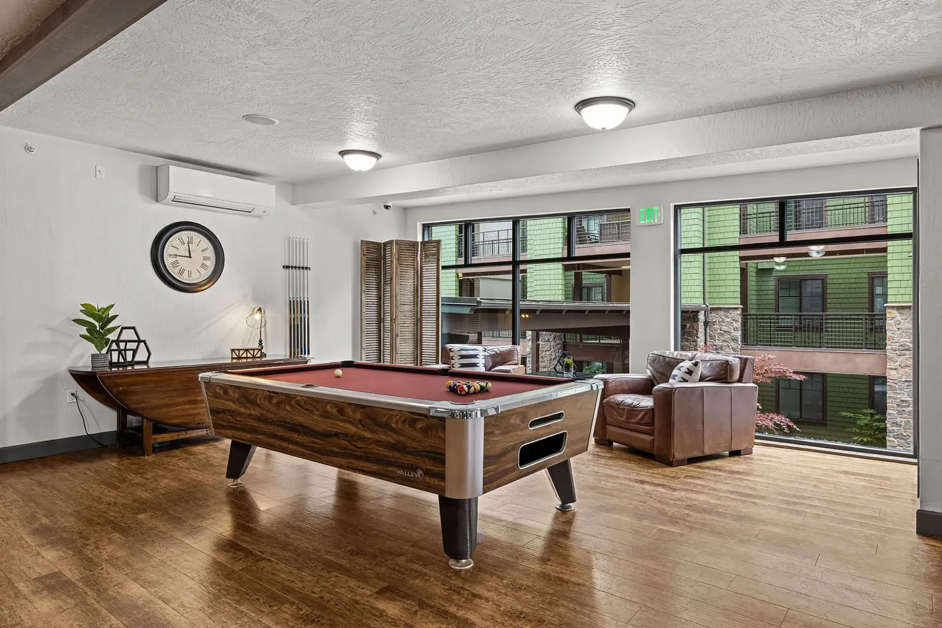 Pool table in common area with seating and large windows.