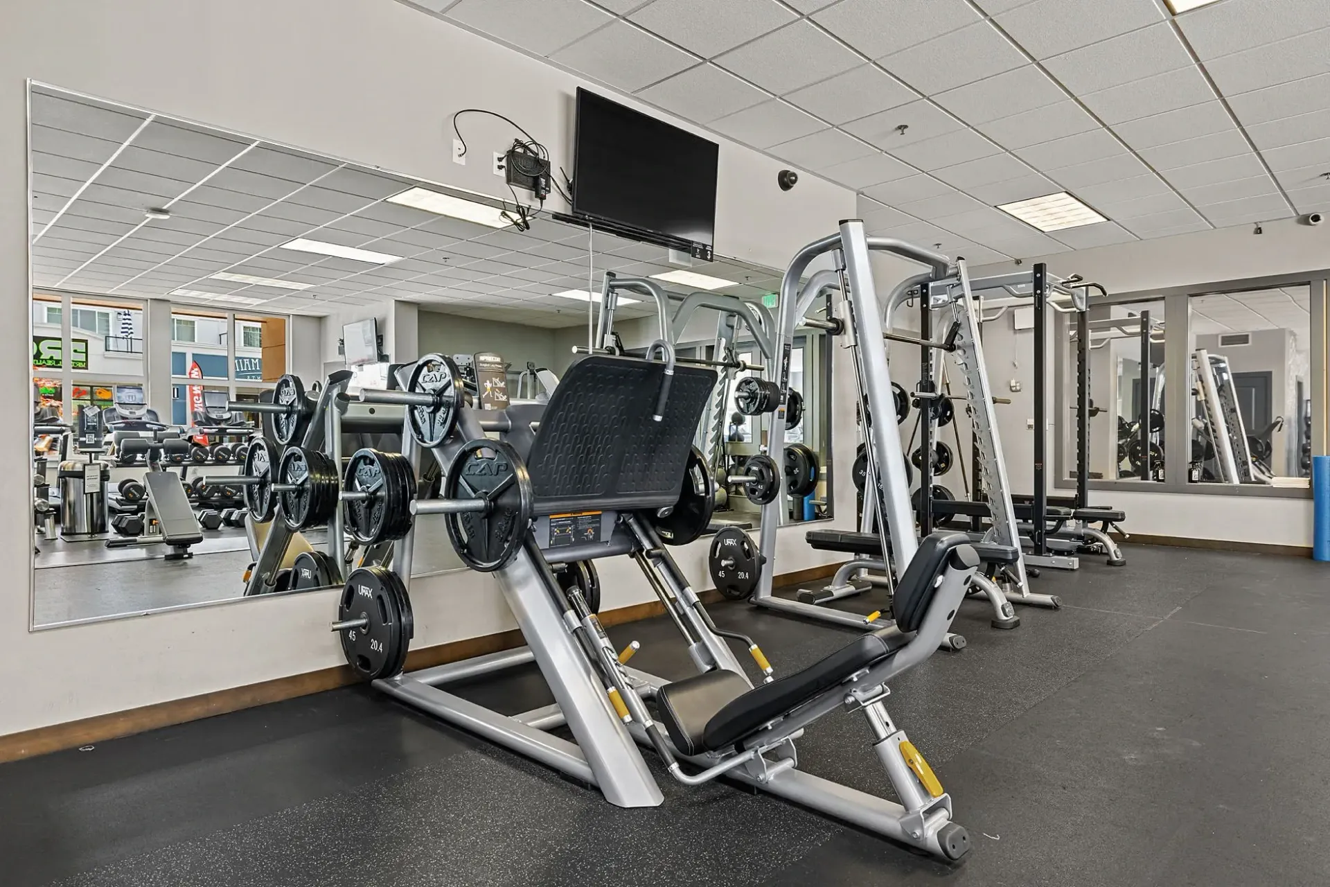 Gym with leg press machine, weights, and mirrors