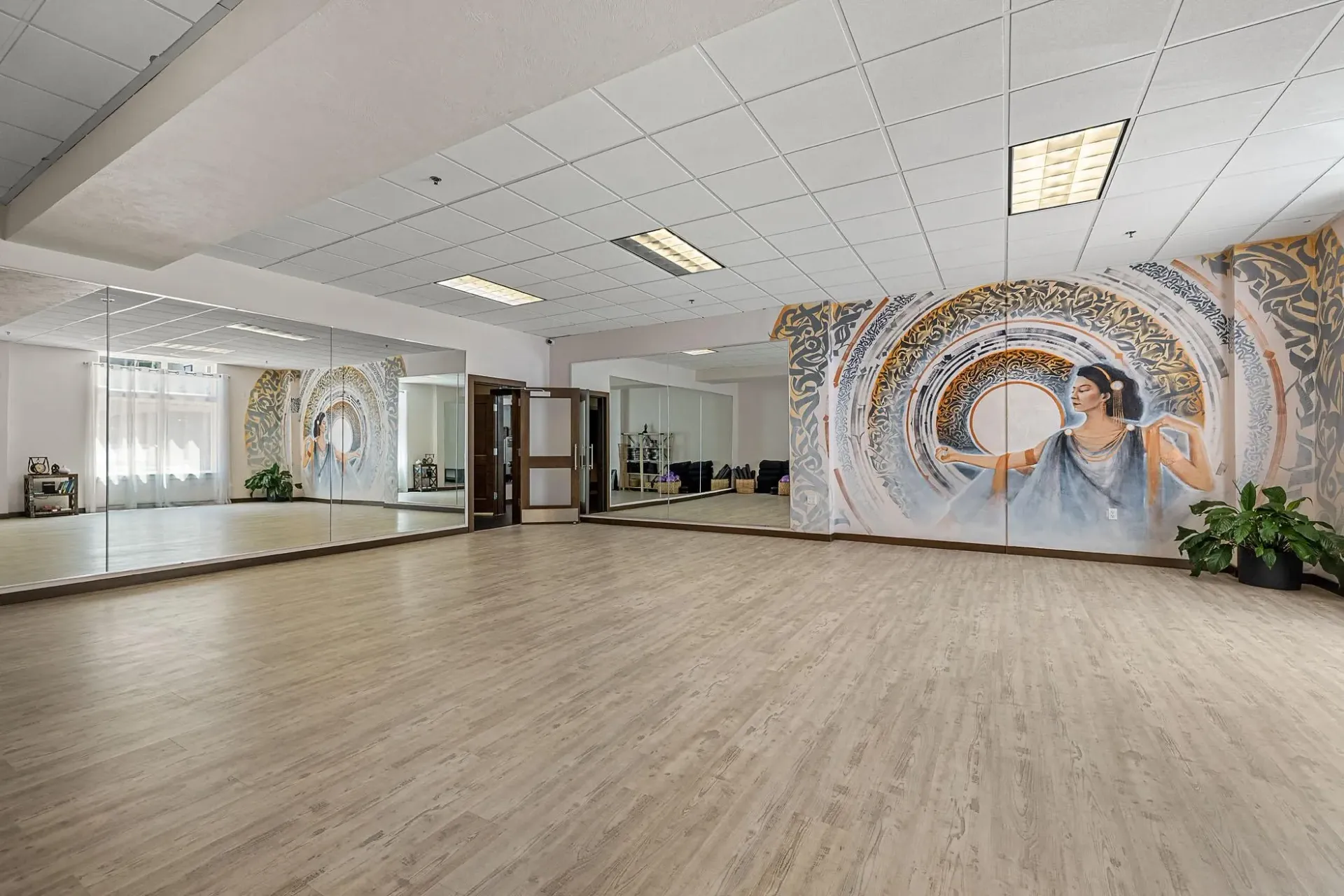 Yoga studio with mirrors and a large mural of a woman.