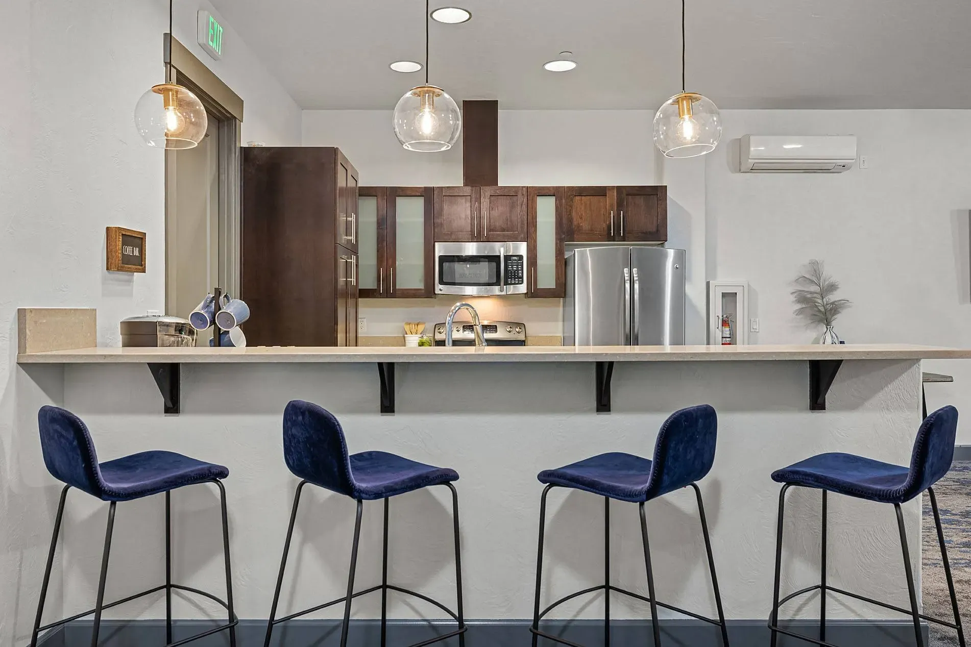 Modern kitchen with stainless steel appliances, dark wood cabinets, and a breakfast bar with blue stools.