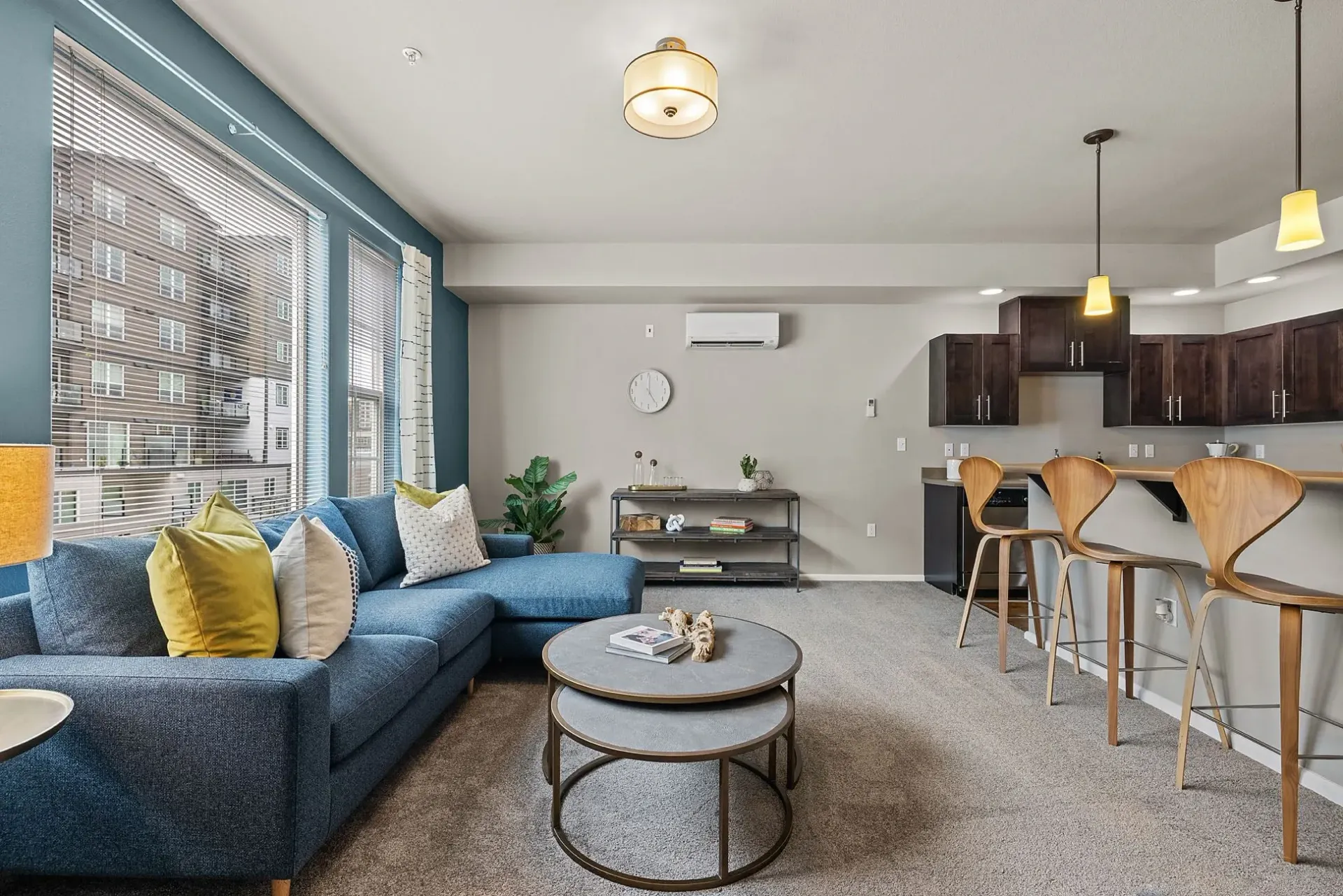 Living room and kitchen area with blue sectional sofa, coffee table, and bar stools.
