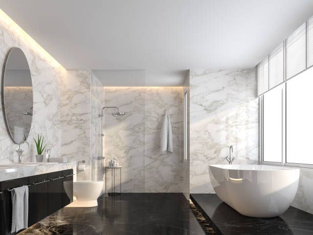 Baño moderno de mármol con bañera independiente, ducha de cristal y grandes ventanales.