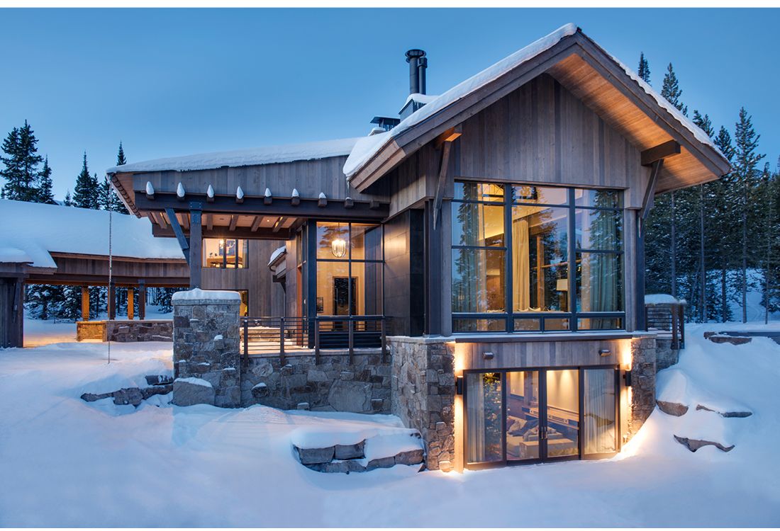 A house with a lot of windows is covered in snow.