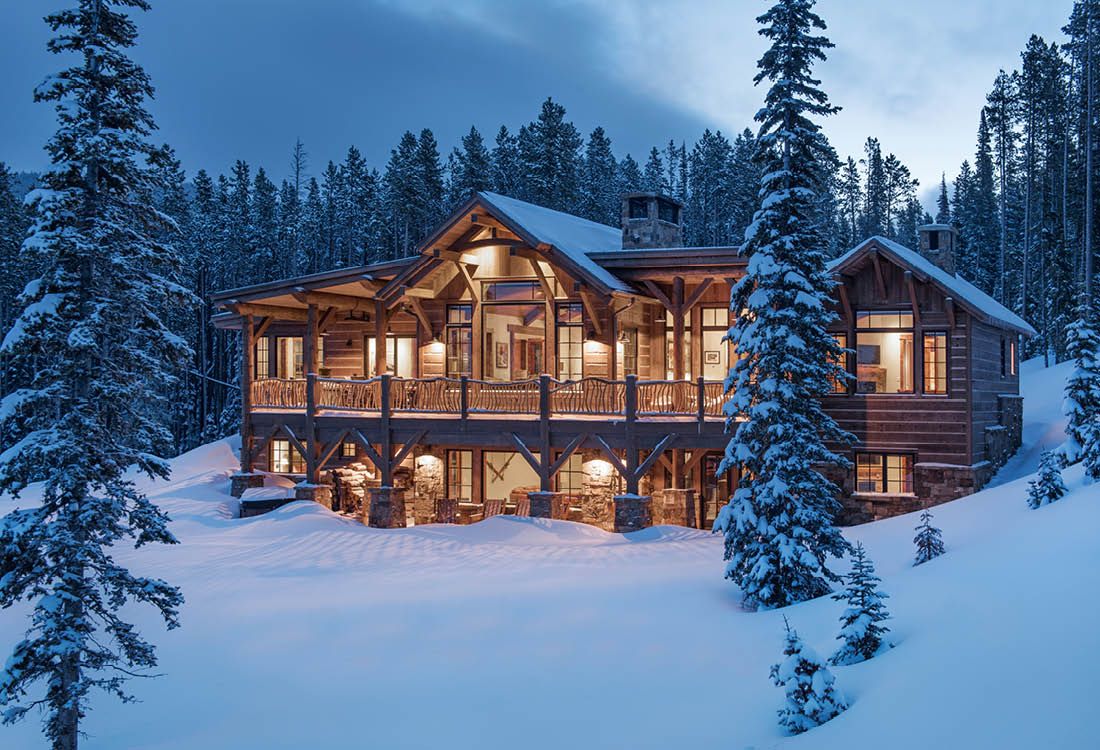 A large log cabin in the middle of a snowy forest.