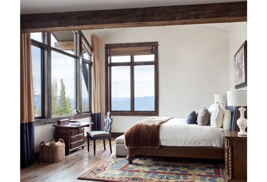 There is a large bed in the middle of the room with a view of the mountains.