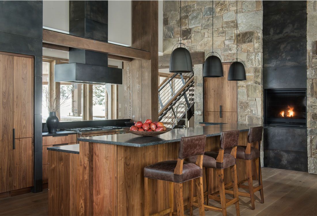 A kitchen with a large island and stools and a fireplace.