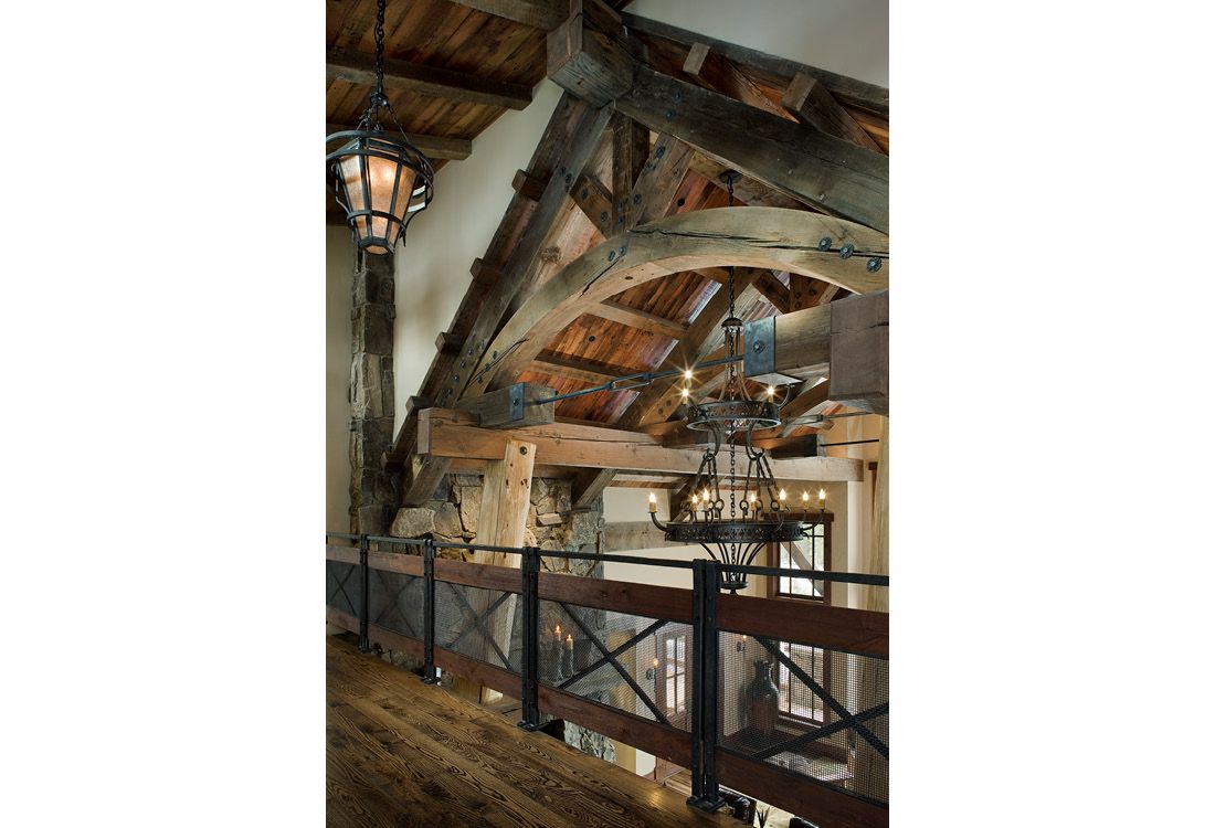 A balcony with a wooden railing and a chandelier hanging from the ceiling.
