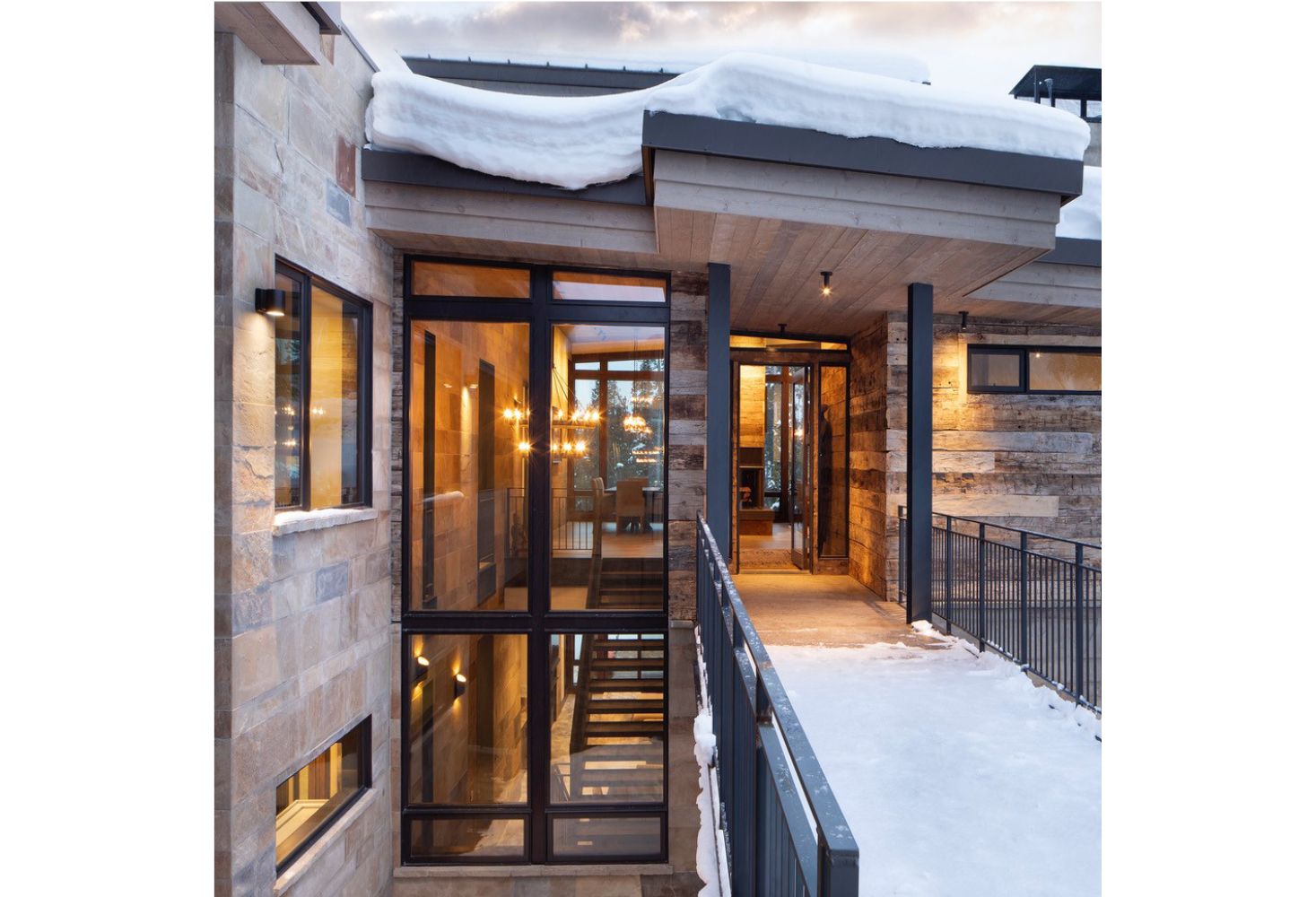A large house with a lot of windows and snow on the roof.