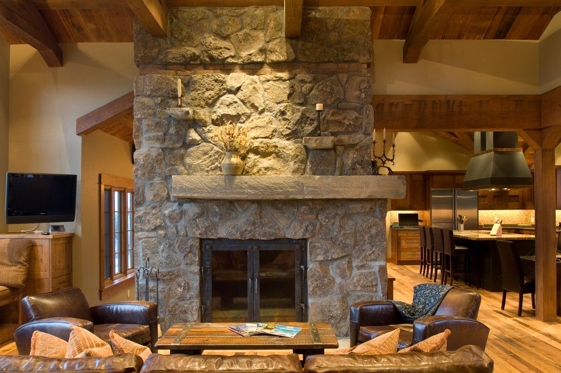 A living room with a large stone fireplace surrounded by furniture