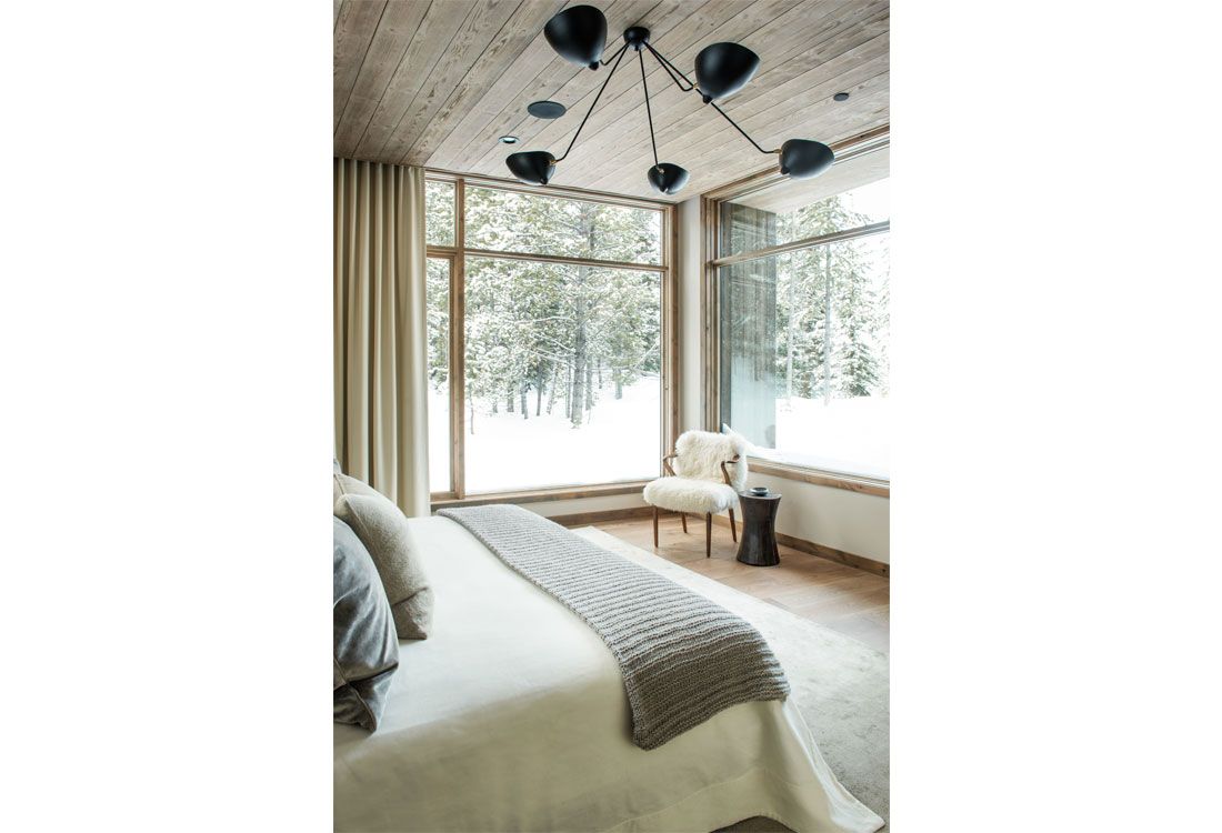 A bedroom with a bed , chair , and large windows.