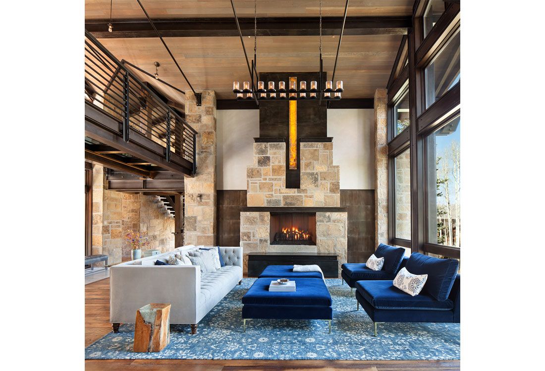 A living room with a fireplace , couch , chairs and ottoman.