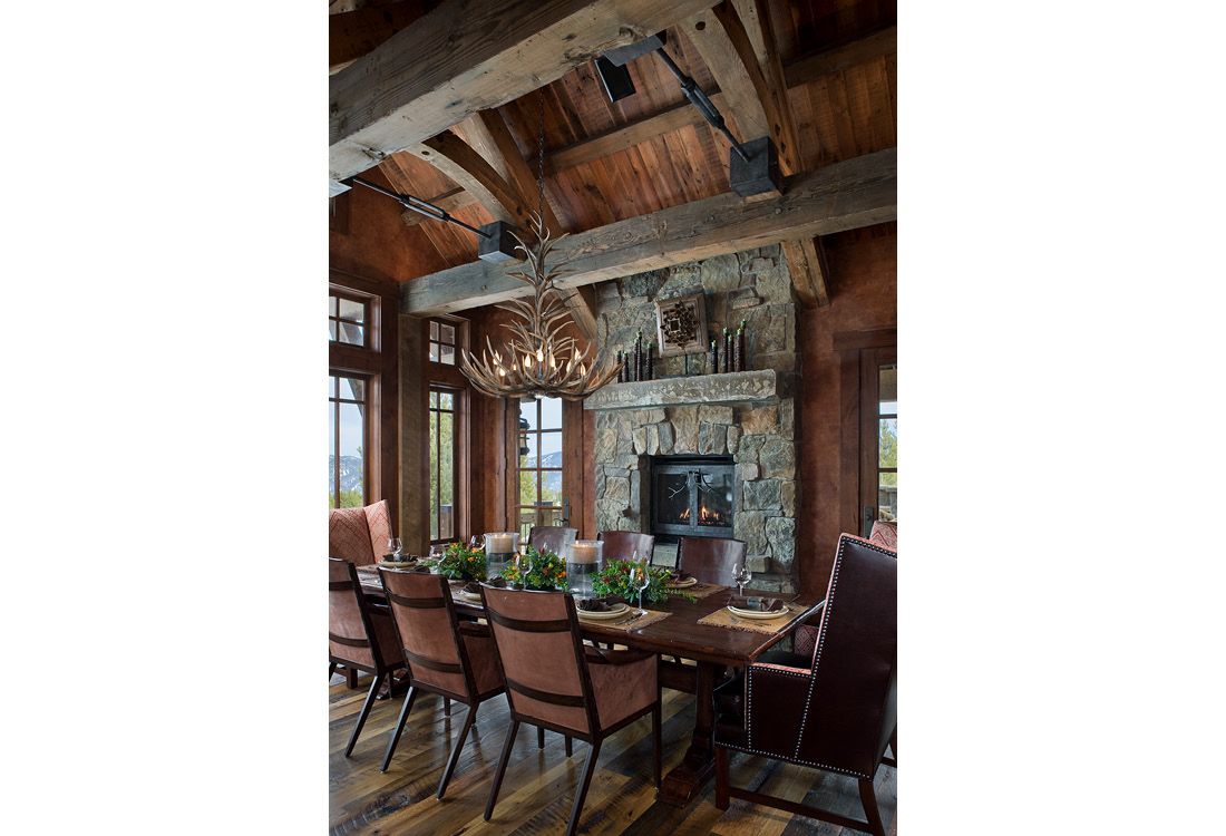 A dining room with a long table and chairs and a fireplace.