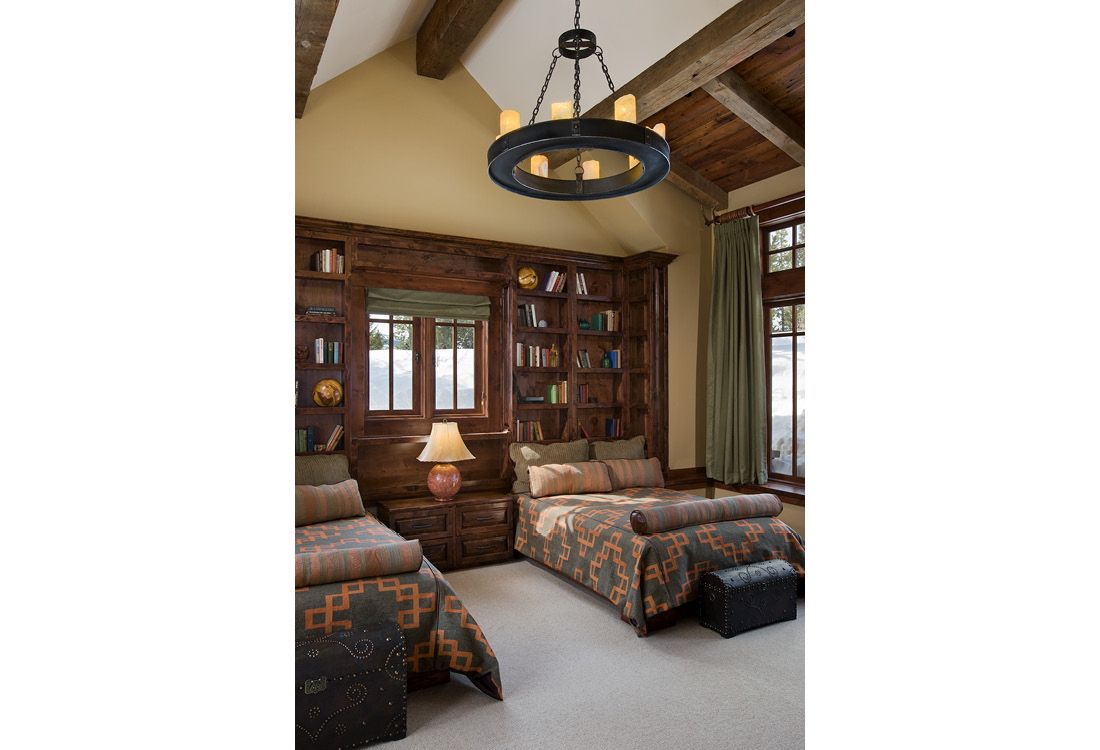 A bedroom with two beds and a chandelier hanging from the ceiling.